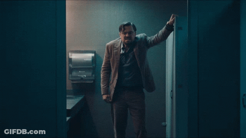 Man Leaning Against Bathroom Wall With Paper Towel Dispenser GIF
