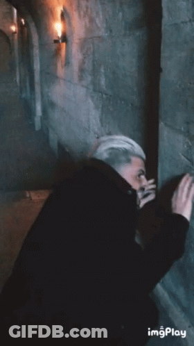Man Leaning Against Stone Wall In Dark Room GIF