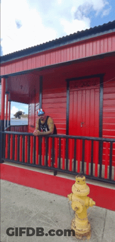 Man Leaning On Red Railing By Fire Hydrant GIF