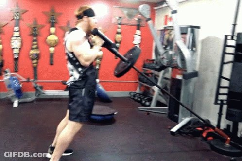 Man Lifting Barbell In Red Wall Gym GIF