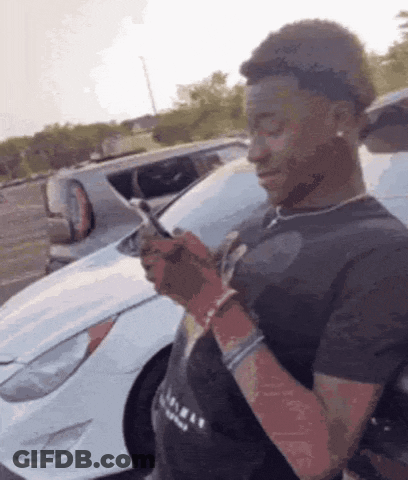 Man Looking At Cell Phone In Front Of White Car GIF