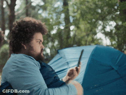 Man Looking At Phone By Blue Tent GIF