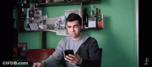 Man Looking At Phone By Green Wall GIF