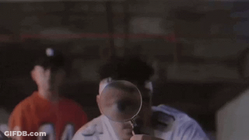 Man Looking Through Magnifying Glass At Another Man's Face GIF
