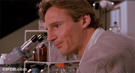 Man Looking Through Microscope With Blue Bottle GIF