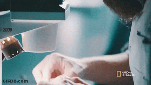 Man Looking Through Microscope With National Geographic Logo GIF