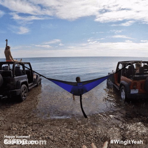 Man Lying In Hammock Between Two Jeep Wranglers On Beach GIF