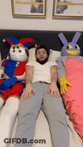 Man Lying On Bed Next To Stuffed Animals GIF