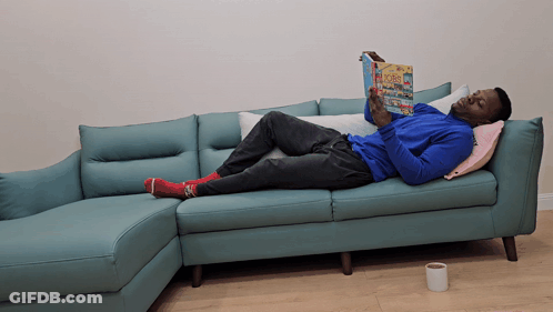 Man Lying On Blue Couch Reading Poes GIF