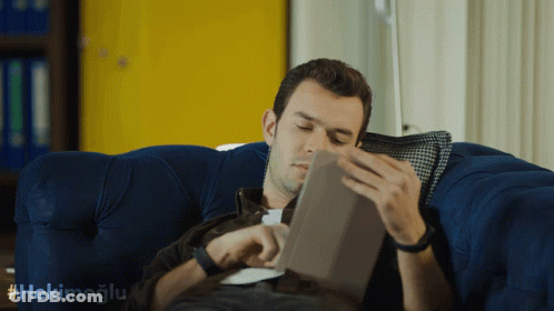 Man Lying On Blue Couch Reading Tablet GIF