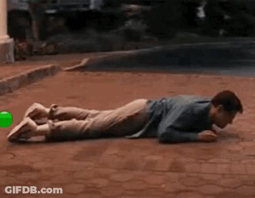Man Lying On Brick Sidewalk With Green Ball GIF