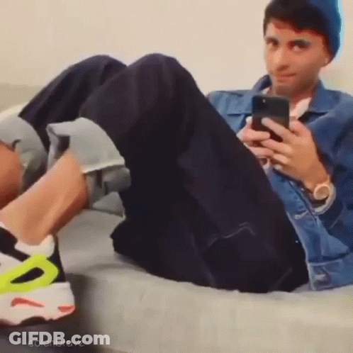 Man Lying On Couch Looking At Phone GIF