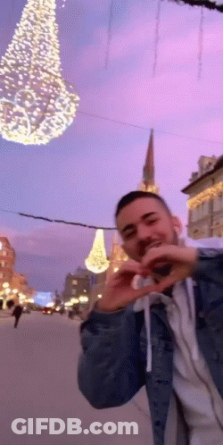 Man Making Heart With Hands In Front Of Christmas Tree GIF