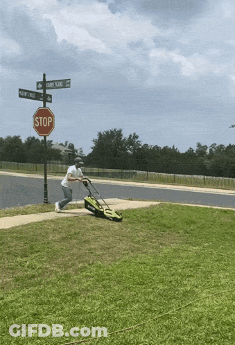 Man Mowing Green Lawn Near Stop Sign GIF