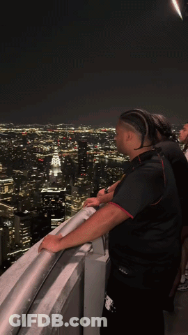 Man On Balcony Overlooking City At Night GIF