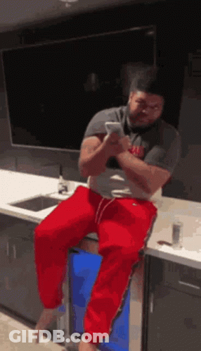 Man On Bar Stool Looking At Phone GIF