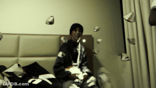 Man On Bed Surrounded By Papers Including Number 7 GIF