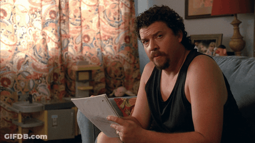 Man On Couch Holding Paper With Sticker Saying A GIF