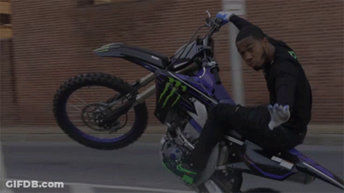 Man On Dirt Bike Doing Handstand In Front Of Stop Sign GIF