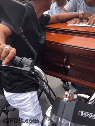 Man On Motorcycle Carrying Coffin With Suzuki Logo GIF