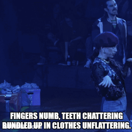 Man On Stage Fingers Numb Teeth Chattering Bundled Up In Clothes Unflattering GIF