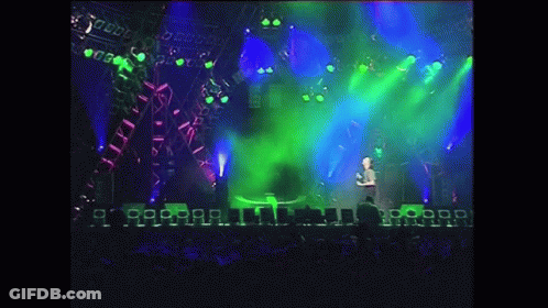 Man On Stage With Green Light And Crowd GIF