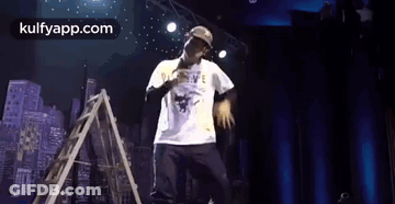 Man On Stage With Microphone And Ladder GIF