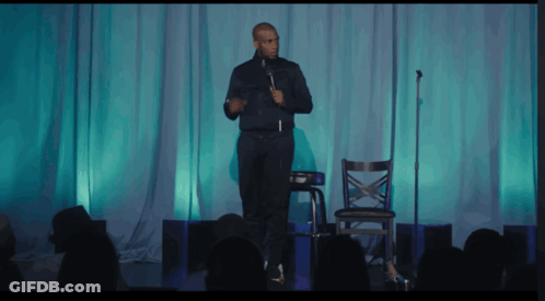 Man On Stage With Microphone In Front Of Crowd GIF