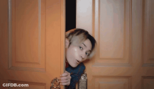 Man Peeking Behind Wooden Door GIF