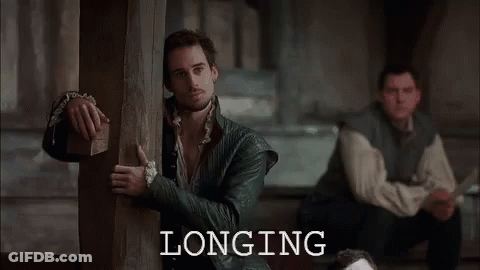 Man Peeking Behind Wooden Post, Another Man Sitting GIF