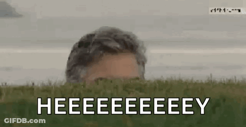 Man Peeking From Behind Grassy Hill Saying Heeeeeeeey GIF