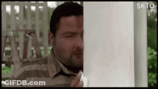 Man Peeking From Behind White Pole GIF