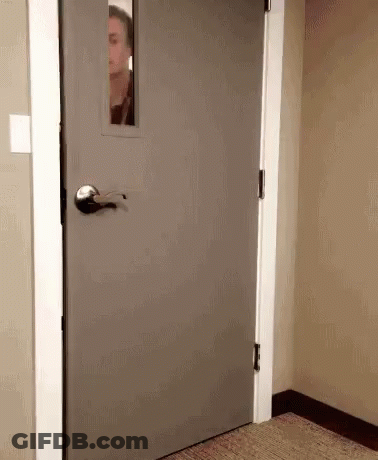 Man Peeking Out Of Gray Door With Window GIF