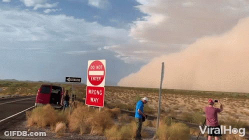 Man Photographing Do Not Enter And Wrong Way Signs GIF