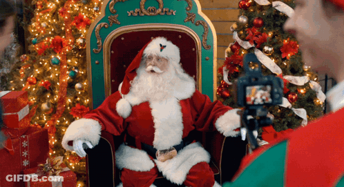 Man Photographing Santa Claus By Christmas Tree GIF
