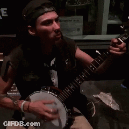 Man Playing Banjo In Front Of Christmas Sign GIF
