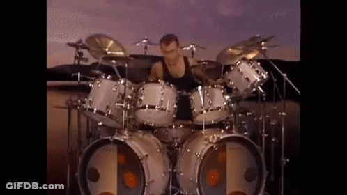 Man Playing Drum Set In Front Of Large Speaker GIF