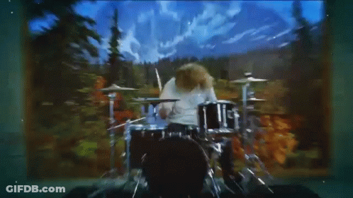 Man Playing Drum Set In Front Of Mountains GIF
