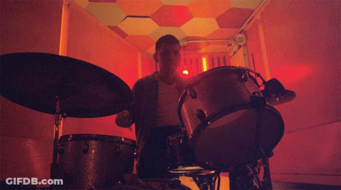 Man Playing Drums In Dark Room With Red Light GIF