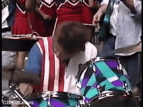Man Playing Drums In Front Of Cheerleader GIF