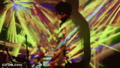 Man Playing Drums In Front Of Colorful Wall GIF