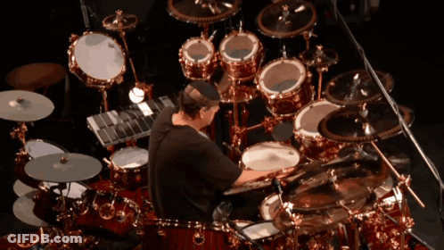 Man Playing Drums In Front Of Large Drum Set GIF