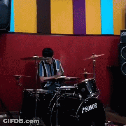 Man Playing Drums In Front Of Red Wall GIF