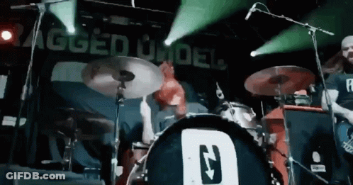 Man Playing Drums In Front Of Rugged Under Sign GIF