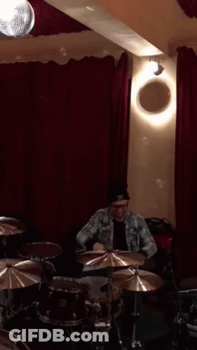Man Playing Drums In Room With Red Curtains GIF