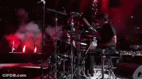 Man Playing Drums On Stage With Red Lights GIF