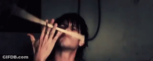 Man Playing Flute In Dark Room With Mask GIF
