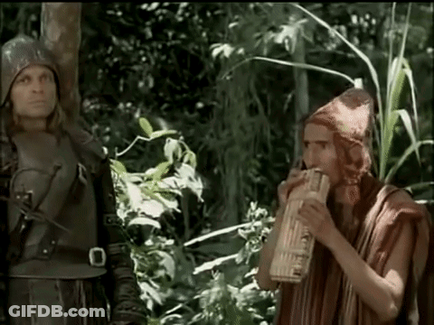 Man Playing Flute In Woods With Another Man GIF