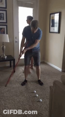 Man Playing Golf In Living Room While Another Watches GIF