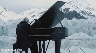 Man Playing Grand Piano In Front Of Snowy Glacier GIF